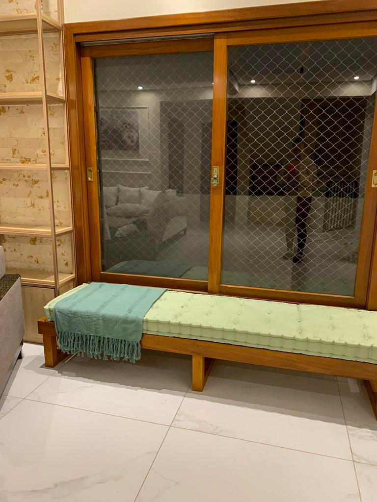 Futon verde com capitonê sobre banco de madeira